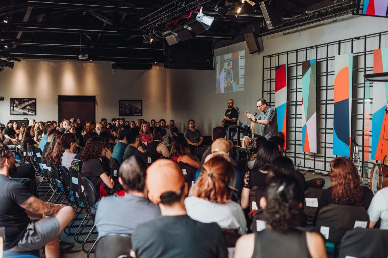 A dynamic group session in a modern auditorium with diverse participants engaged with a speaker.